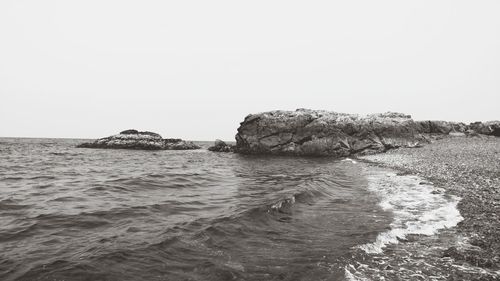 Rocks in sea against clear sky