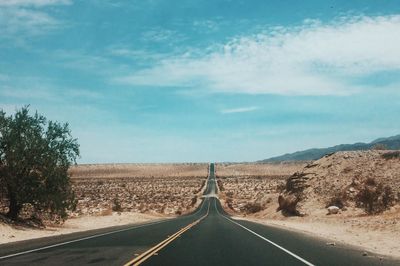 Empty road by landscape against sky