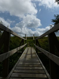 Footbridge leading towards bridge against sky