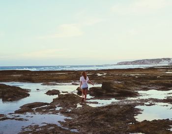 Woman standing on beach against sky