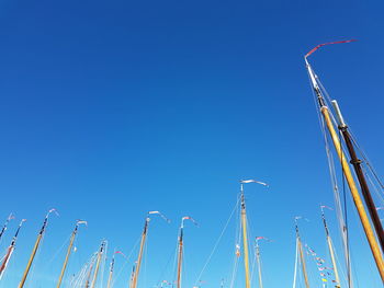 Low angle view of cranes against clear blue sky