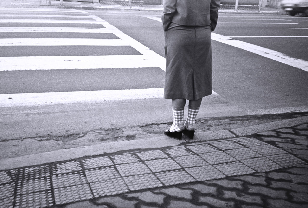 road marking, city, road, low section, street, real people, crosswalk, symbol, crossing, marking, body part, sign, transportation, people, zebra crossing, walking, human leg, lifestyles, day, outdoors, waiting, dividing line
