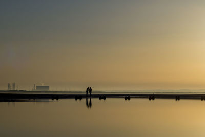 Silhouette people on bridge against sky during sunset