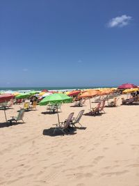 Beach umbrellas on shore against blue sky