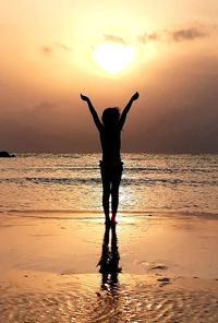 Silhouette man standing on beach against sky during sunset