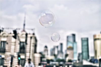 Bubbles against buildings in city against sky