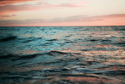 Surface level of sea against sky during sunset