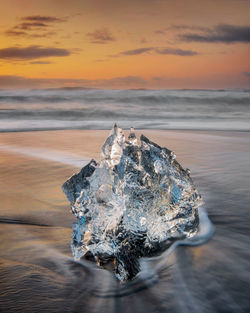 Close-up of ice on beach during sunset