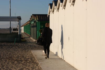 Rear view of man walking on footpath