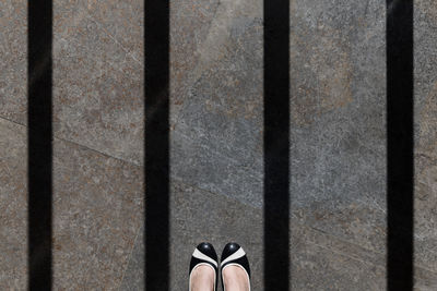 Low section of woman on marble flooring with shadow of prisoner bars