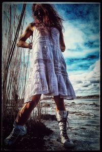 Midsection of woman at beach against sky