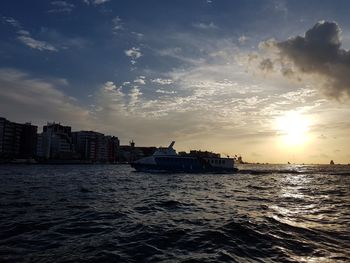 Scenic view of sea by buildings against sky during sunset
