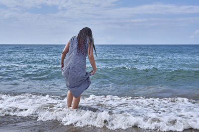 Full length of woman standing on beach against sky