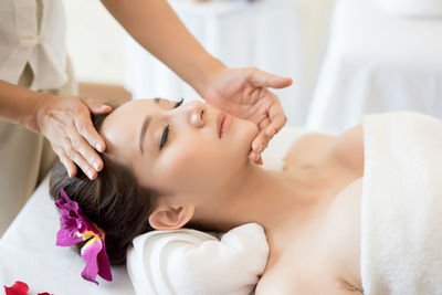 Cropped image of masseur massaging young woman on table