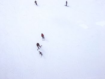 High angle view of people skiing on snow covered landscape against cloudy sky