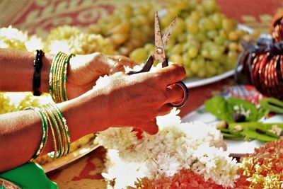 Close-up of hand holding garland and scissors