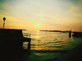 Silhouette boats in sea against dramatic sky during sunset