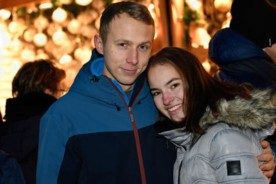 A young couple in love hugs at the christmas market.