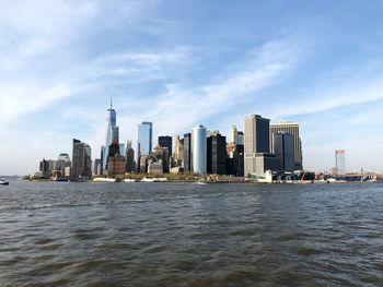 Sea by modern buildings against sky in city