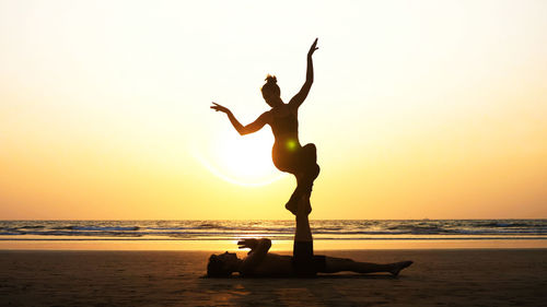 Man and woman doing yoga at beach