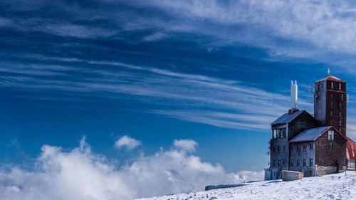 Low angle view of cottage on snow covered house against sky