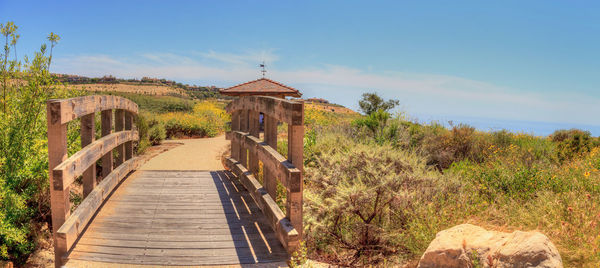 Boardwalk amidst field against sky