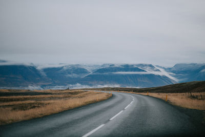 Road by mountains against sky