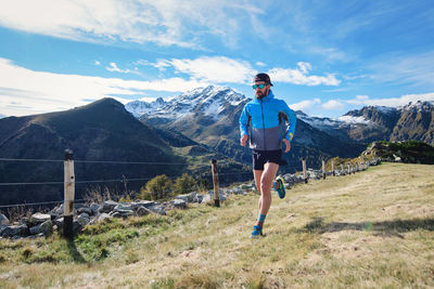 Rear view of man standing on mountain against sky