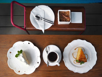 Directly above shot of cakes in plate by coffee cup on table in hotel