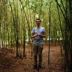 Portrait of man standing amidst trees in forest
