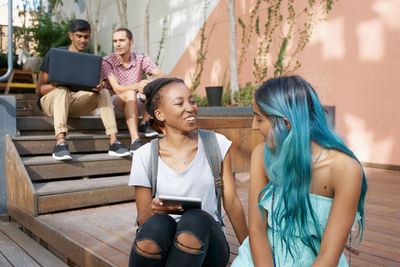 Cheerful friends talking while sitting outdoors