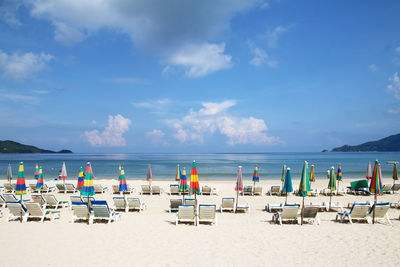 Deck chairs and parasols on beach against sky