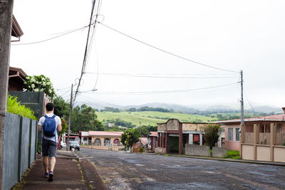 Rear view of people walking on road amidst buildings