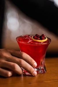 Cropped hand holding drink on table