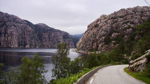 Road amidst trees and mountains against sky