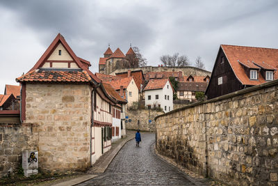 Rear view of woman walking on houses against sky