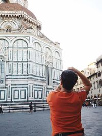 Rear view of man standing outside temple against clear sky