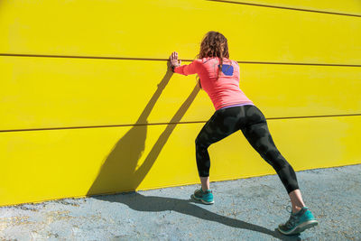 Full length of woman on yellow wall