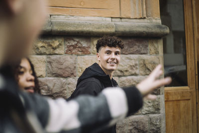 Smiling looking at male friend while walking near stone wall