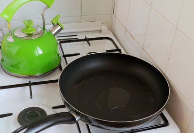 Fry pan with heated olive oil on the stove with a kettle in background