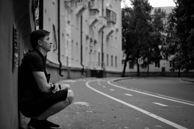 Side view of young woman sitting on street