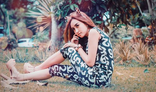 Full length of young woman sitting on land