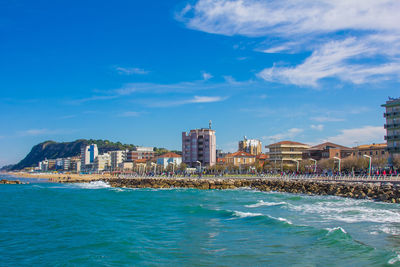 View of buildings at waterfront against cloudy sky