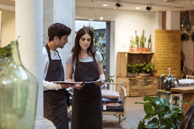 Male and female colleague discussing over digital tablet while standing in boutique