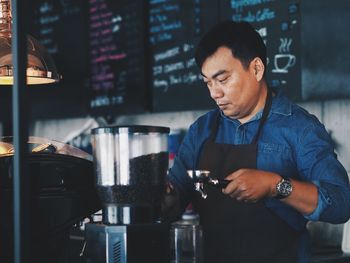 Mature man making coffee at cafe