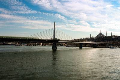 Bridge over river against sky in city