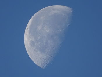 Low angle view of half moon against clear blue sky