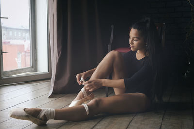 A young gentle and thoughtful ballerina poses in the interior and at the window