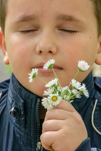 Close-up portrait of boy with flowers in sunlight