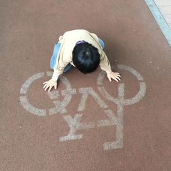 High angle view of boy kneeling on road marking